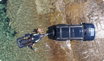 A truck backing a boat into a water.