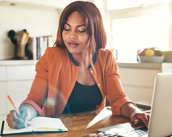 Woman sitting at table writing a home inventory for homeowners insurance.