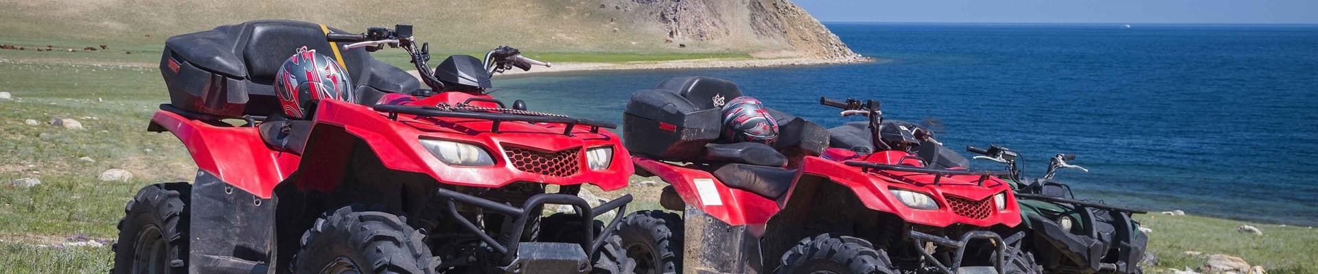 a group of red go karts on a grassy hill by the water